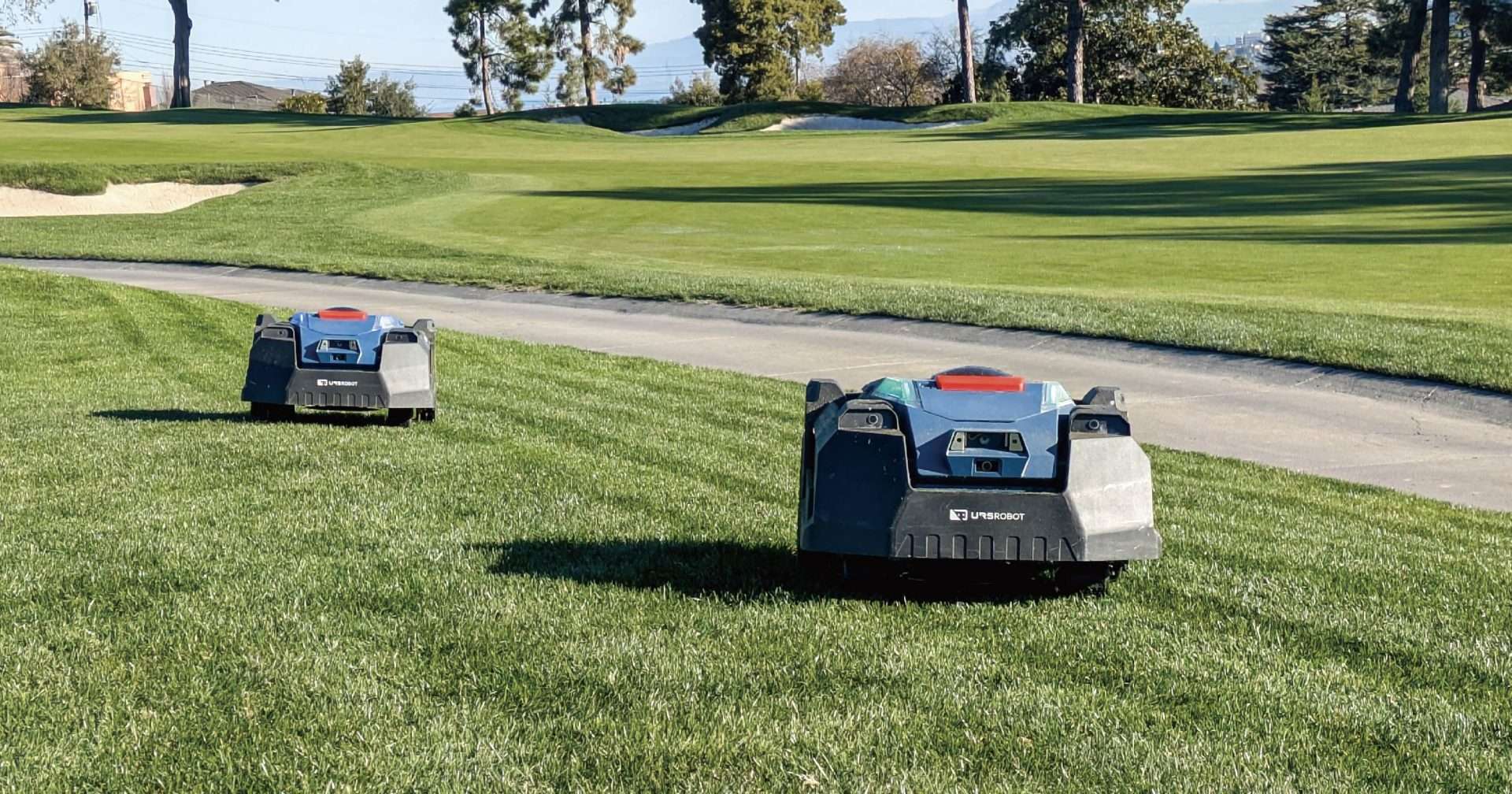 Two URSROBOT robotic mowers operating on a golf course