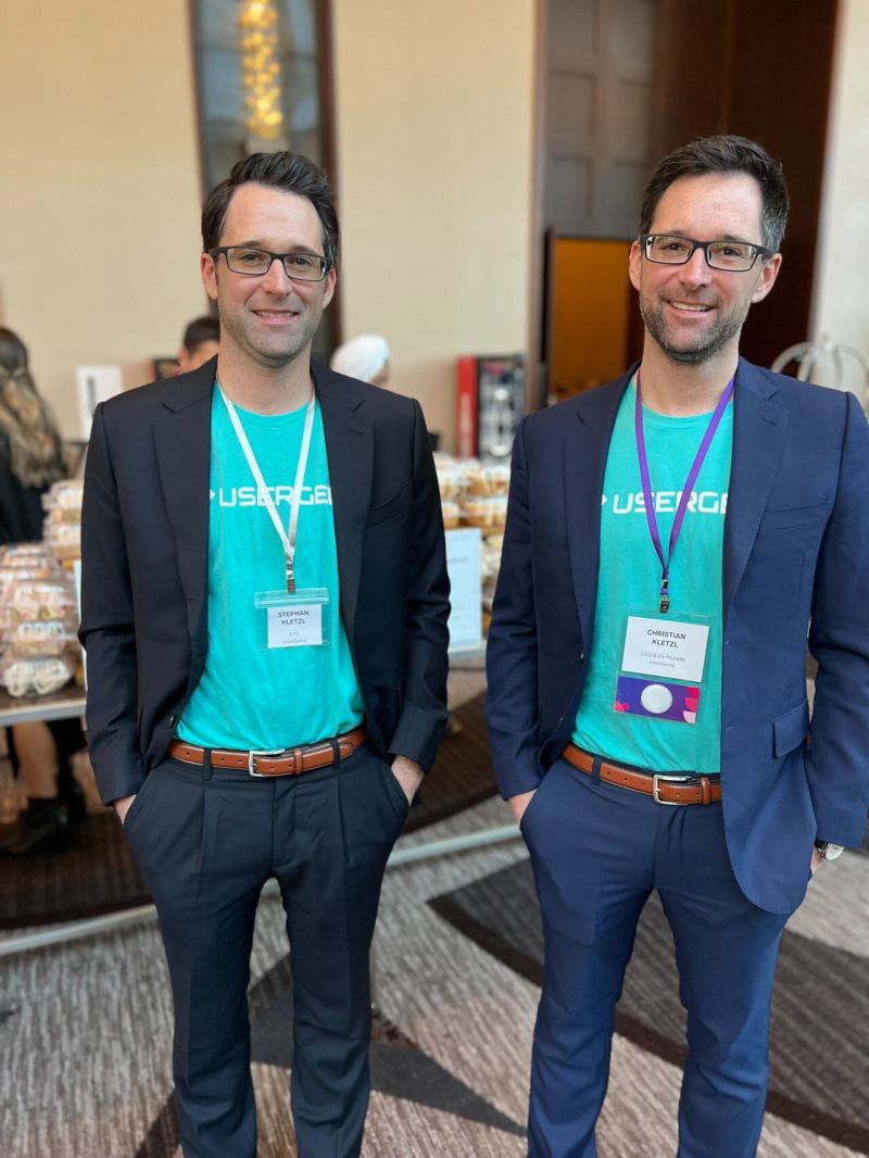 UserGems co-founders Stephan and Christian Kletzl wearing company shirts at a conference