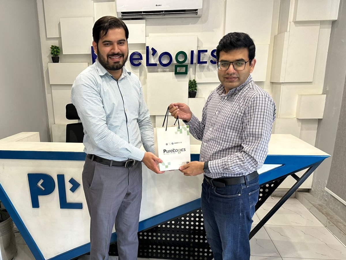 Usman Akbar at right presenting a PureLogics gift bag to a university visitor