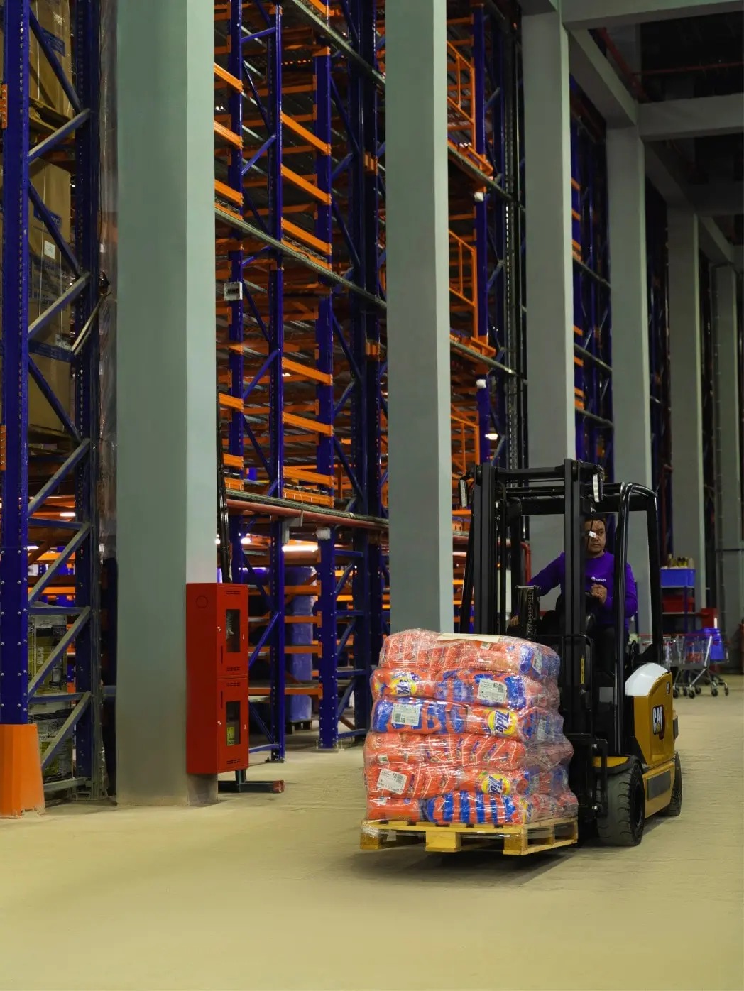 A forklift operator moves goods between tall warehouse racks at Uzum