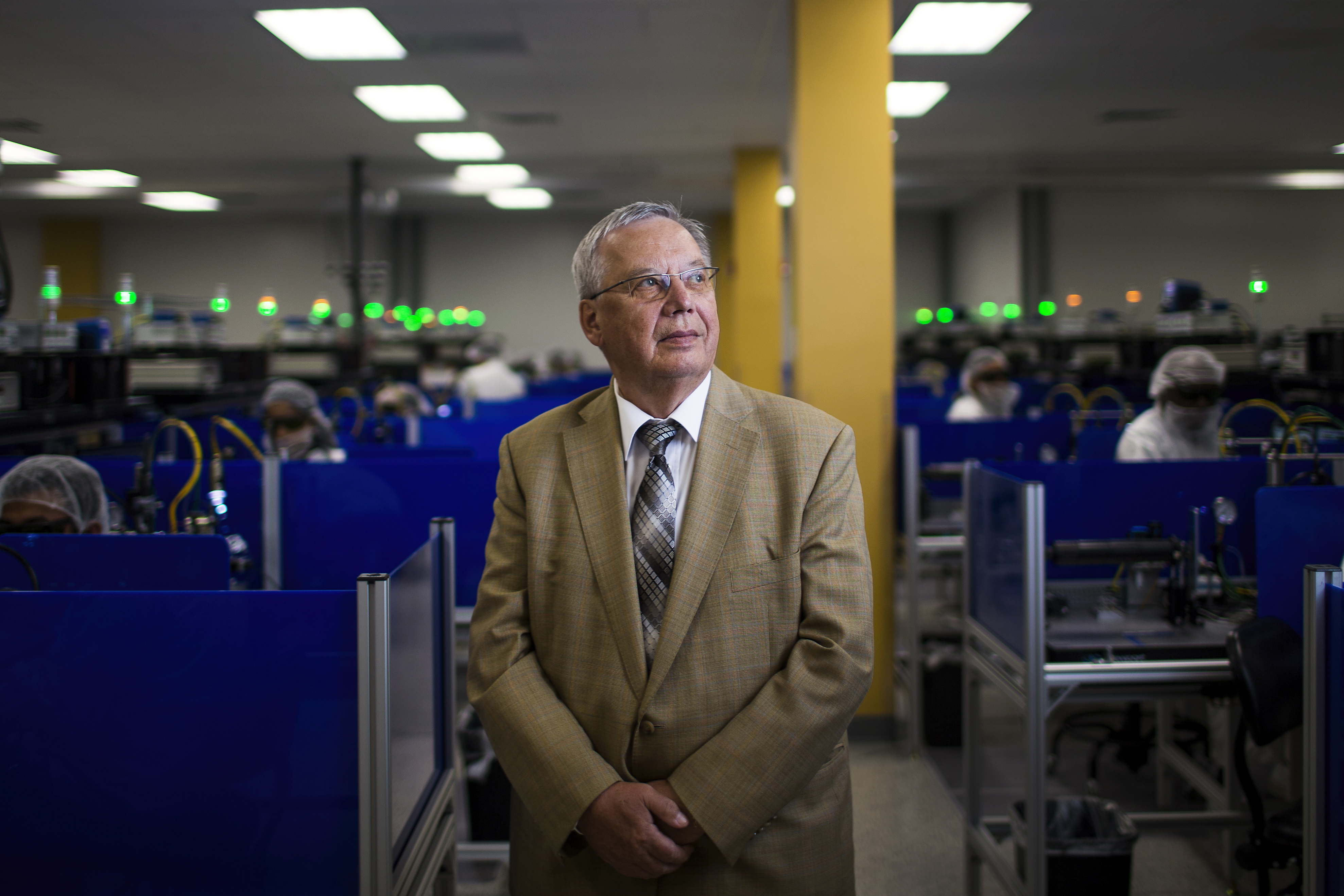 Valentin Gapontsev standing among laser-production workstations at IPG Photonics in Oxford, Massachusetts