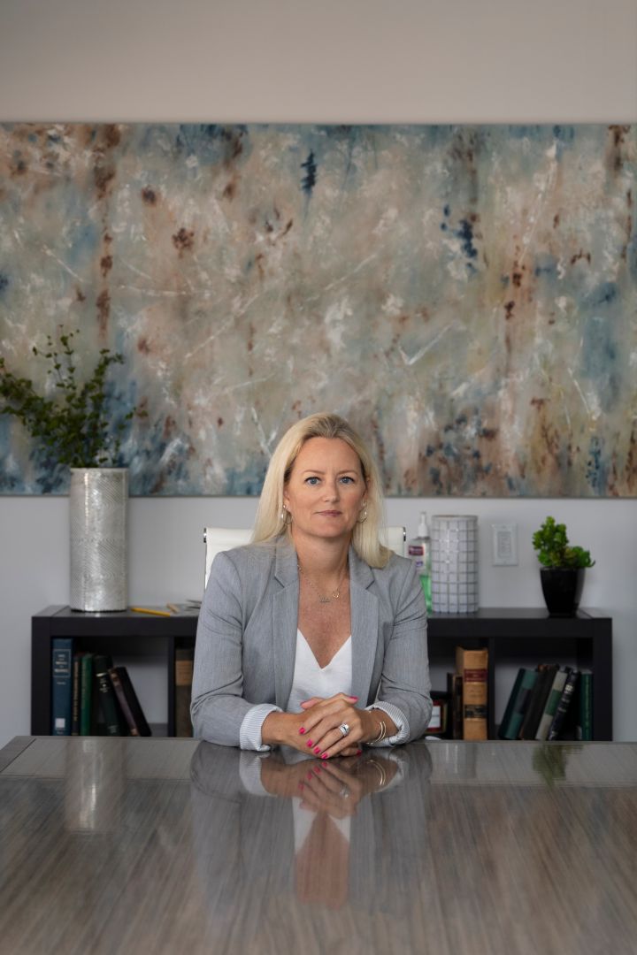 Valerie Christopherson seated at a conference table in an office, with abstract artwork behind her