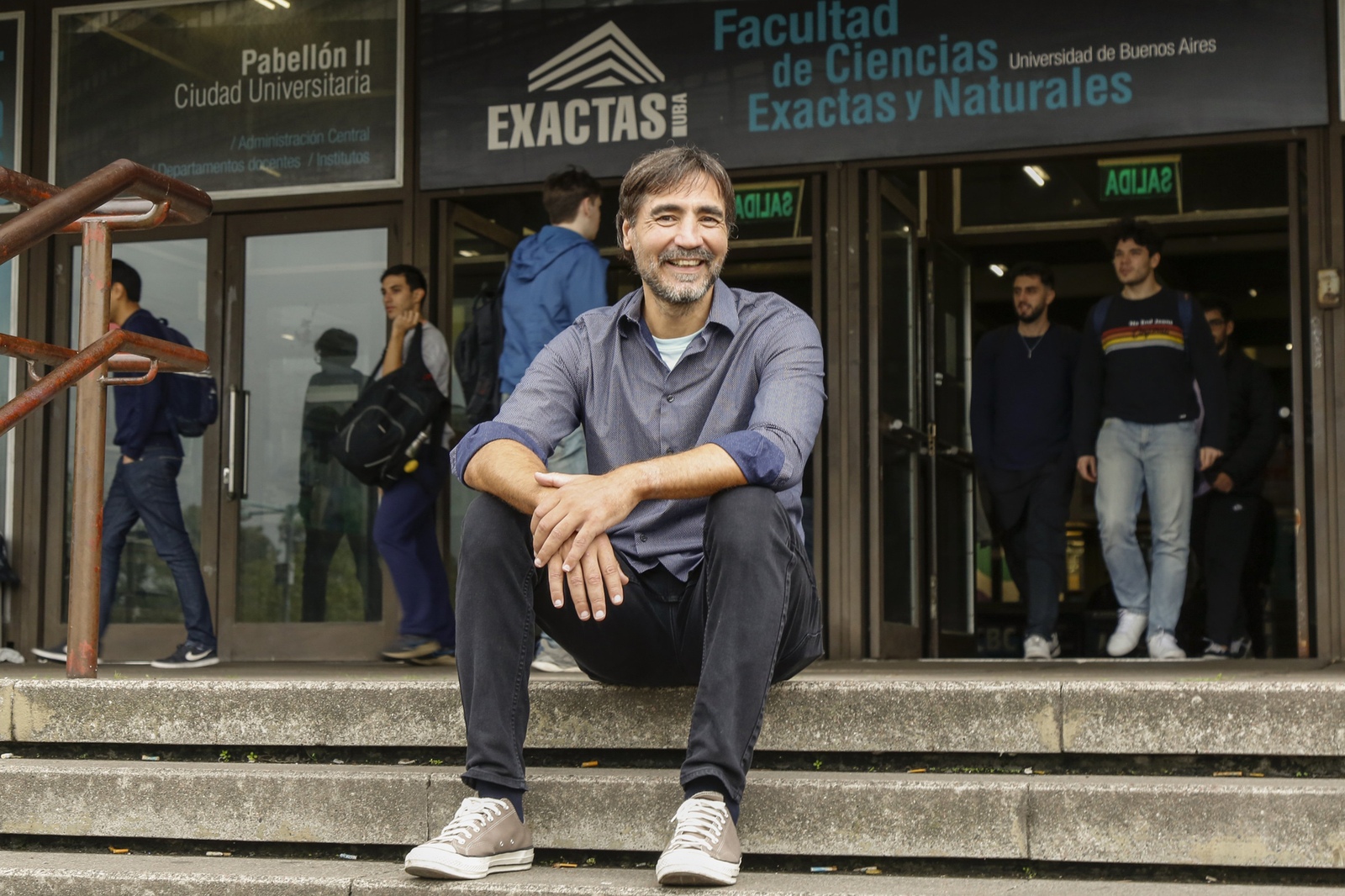 Adrián Anacleto sitting on the steps outside the Faculty of Exact and Natural Sciences at the University of Buenos Aires