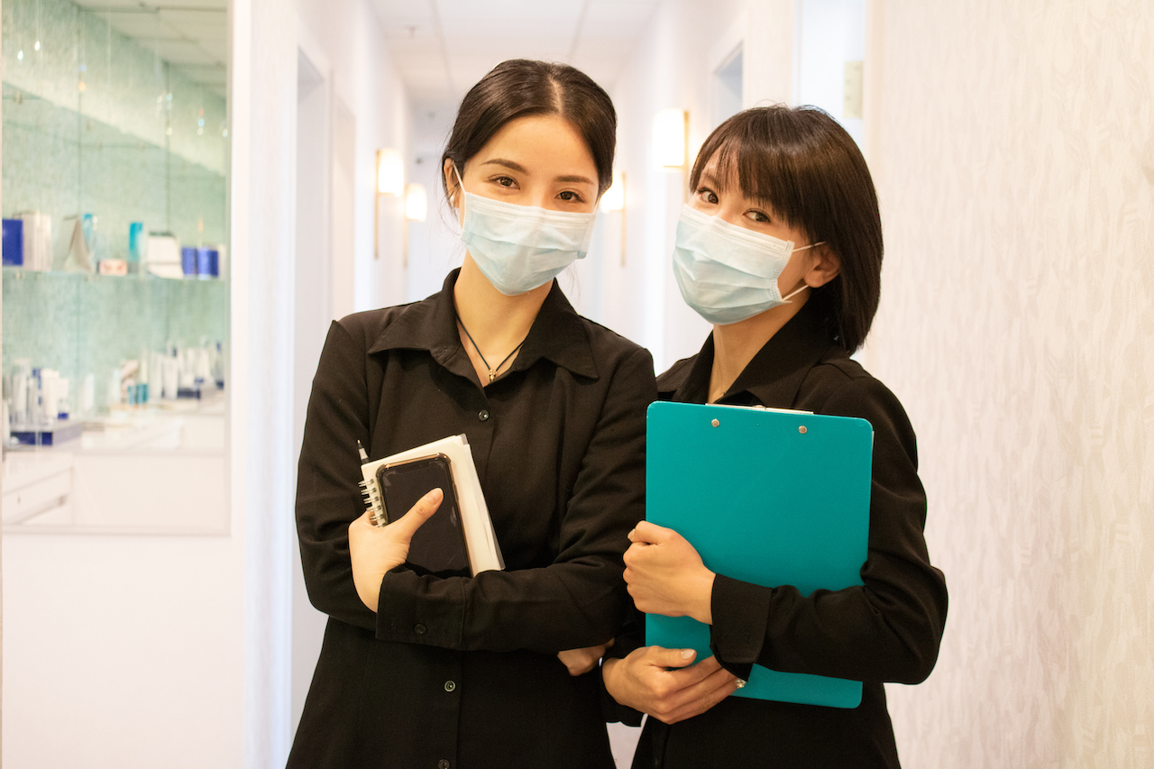 Two Vancouver Laser team members standing in a bright clinic corridor