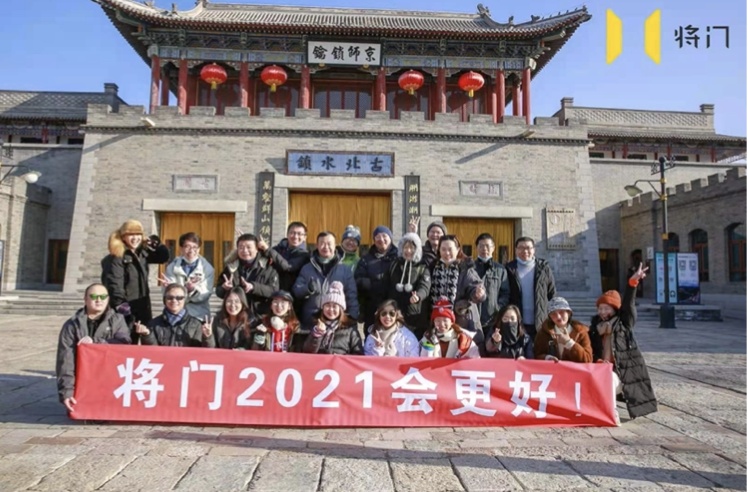 The Jiangmen team posing together outside a traditional Chinese building with a red 2021 banner