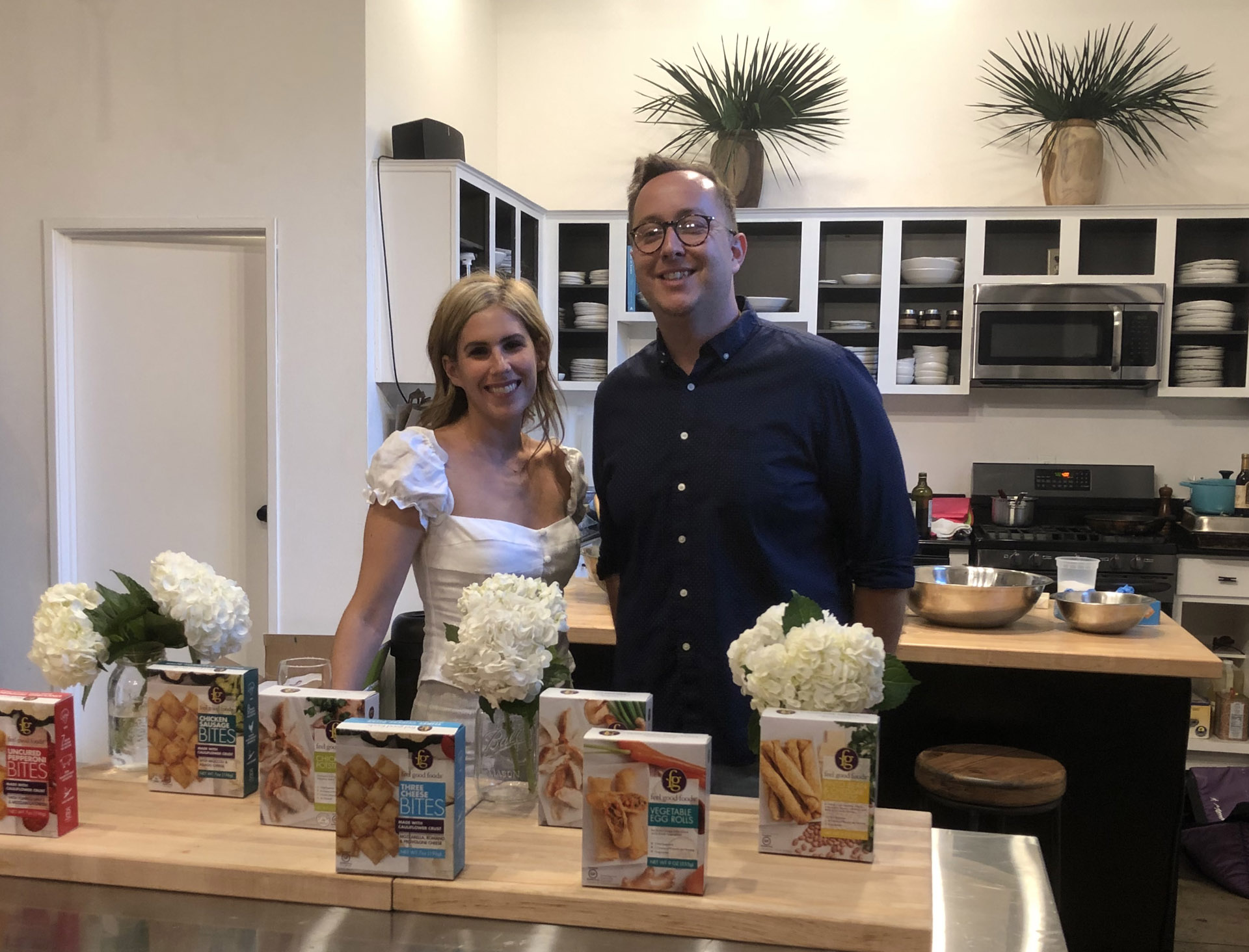 Vanessa Phillips and Eater LA editor Farley Elliott standing behind Feel Good Foods products at a press event