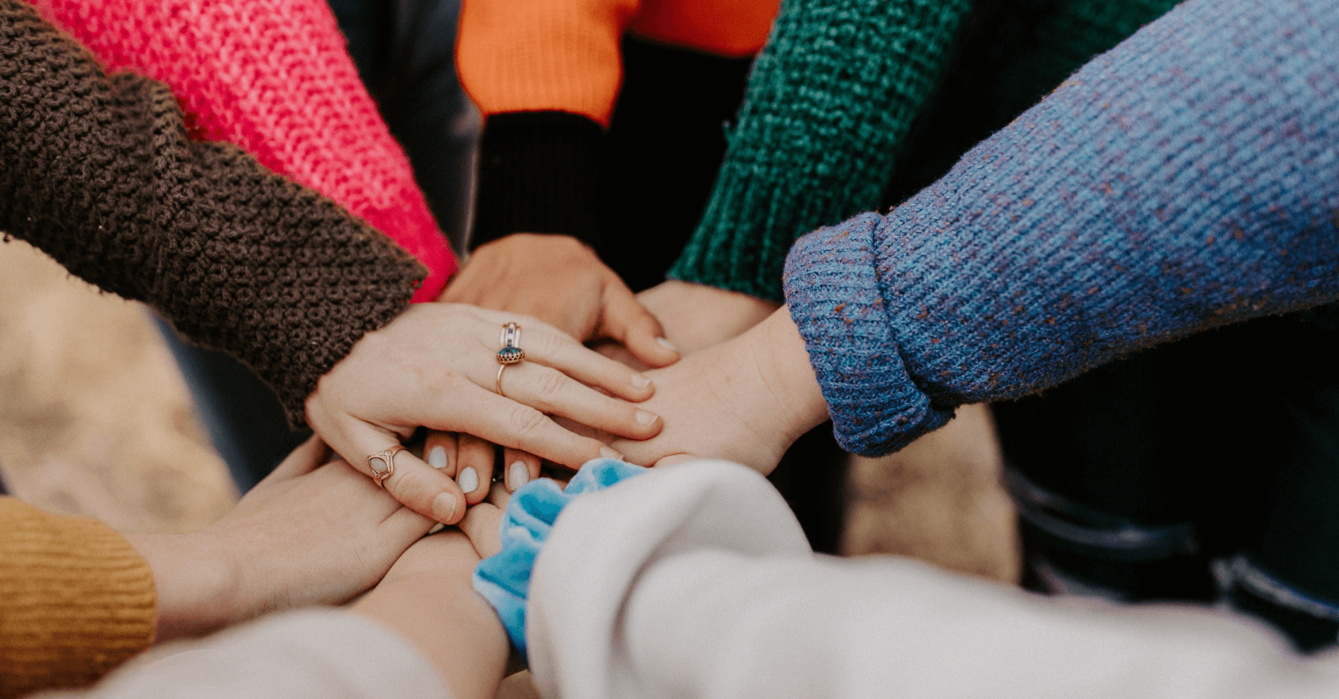 A circle of people stacking their hands together