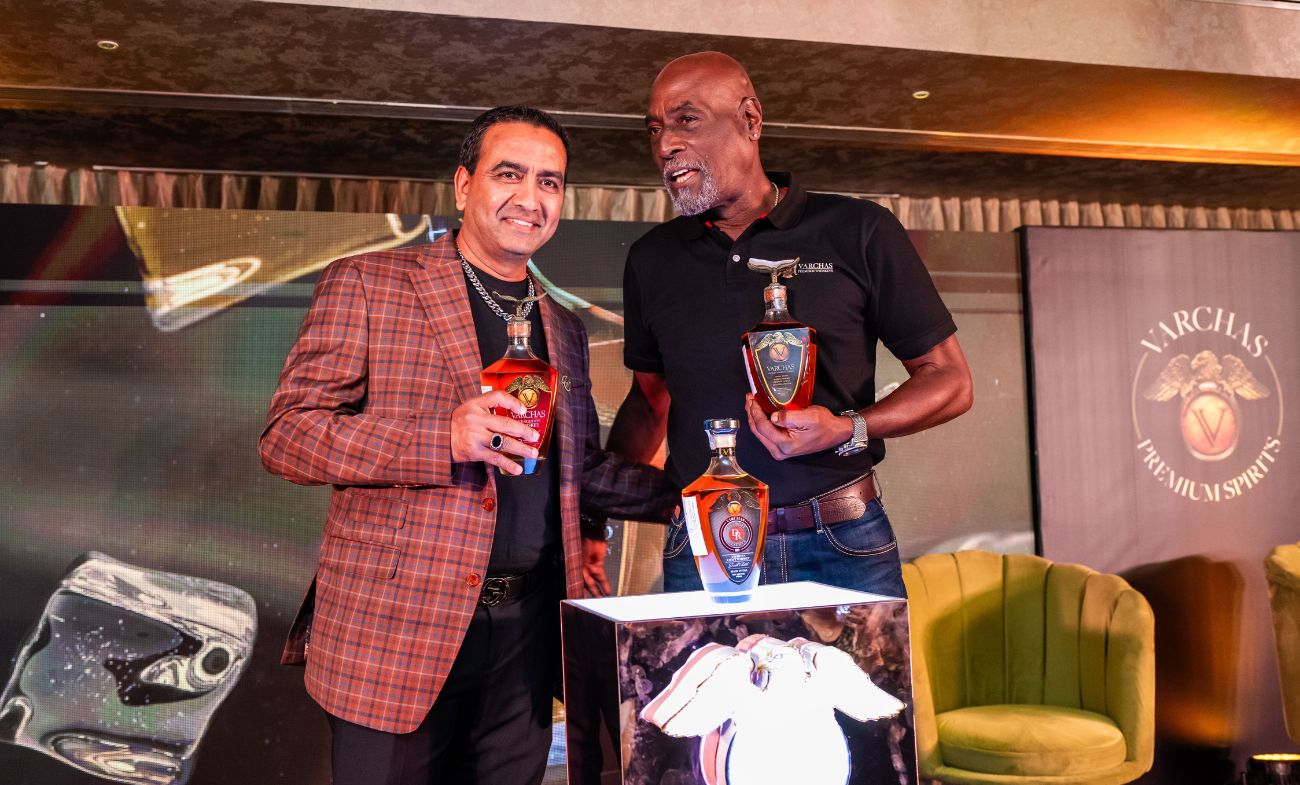 Varchasvi Shankar at left with Sir Vivian Richards, both holding Varchas bottles at a brand event