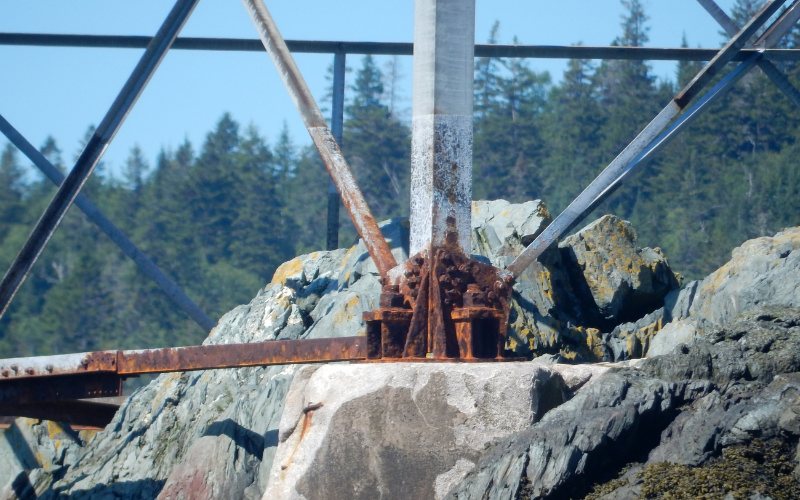 A badly corroded tower leg and bracing anchored into rock on a Bay of Fundy island
