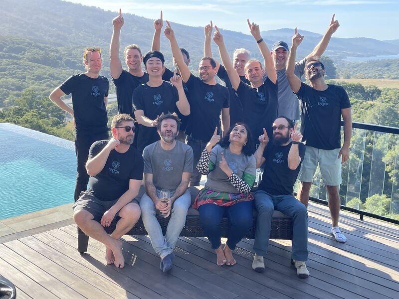 Early Endor Labs team gathered outdoors beside a pool, with several people pointing toward the sky