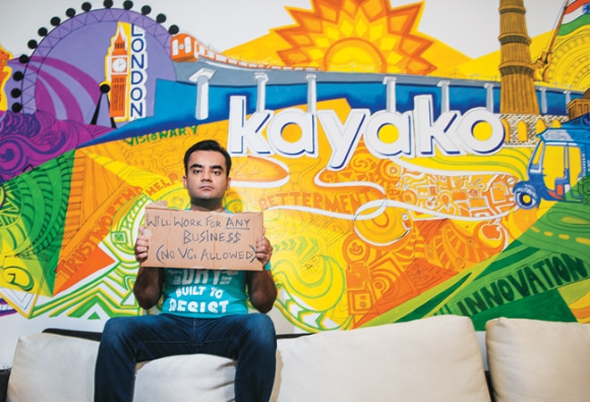 Varun Shoor on a sofa at Kayako’s Gurgaon office, holding a cardboard sign saying no VCs allowed.