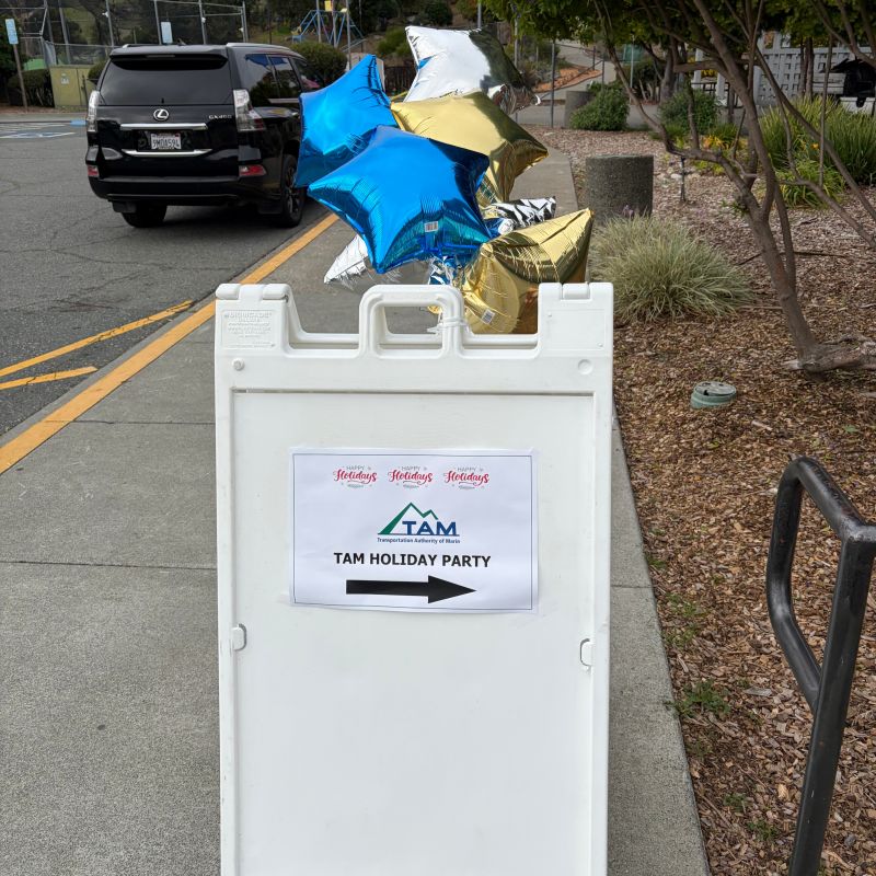A sign pointing toward the TAM holiday party, topped with metallic star balloons