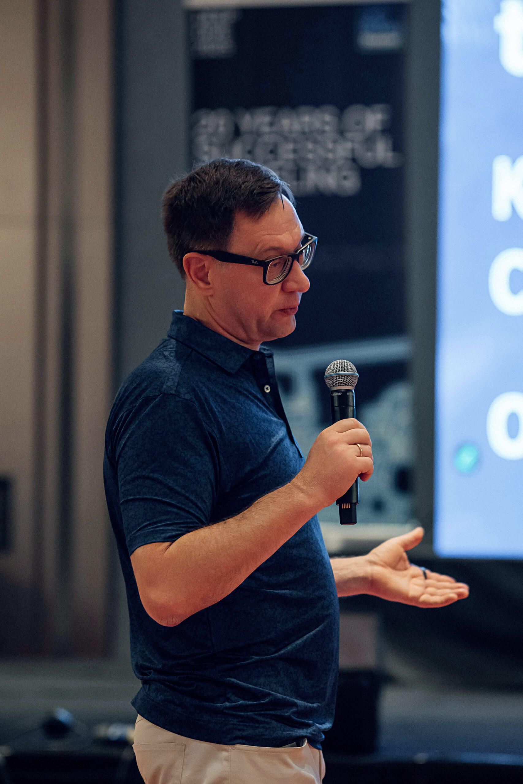 Vasilii Shelkov speaking into a microphone at a Rock Flow Dynamics Technology Summit