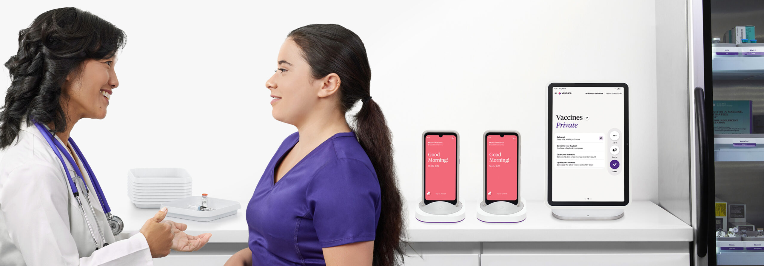 VaxCare promotional image showing clinicians beside Hub and Mobile Hub devices and a vaccine refrigerator