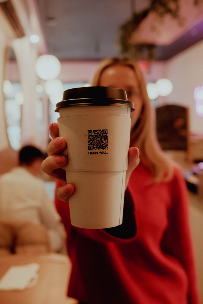 A QR-coded coffee cup held toward the camera during the VaynerSpeakers and Kofee collaboration