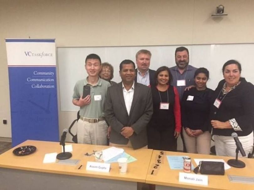 A group at a VC Taskforce gathering behind a table with microphones and name cards