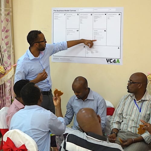 Workshop participants discuss a business model canvas in a photograph published by VC4A.