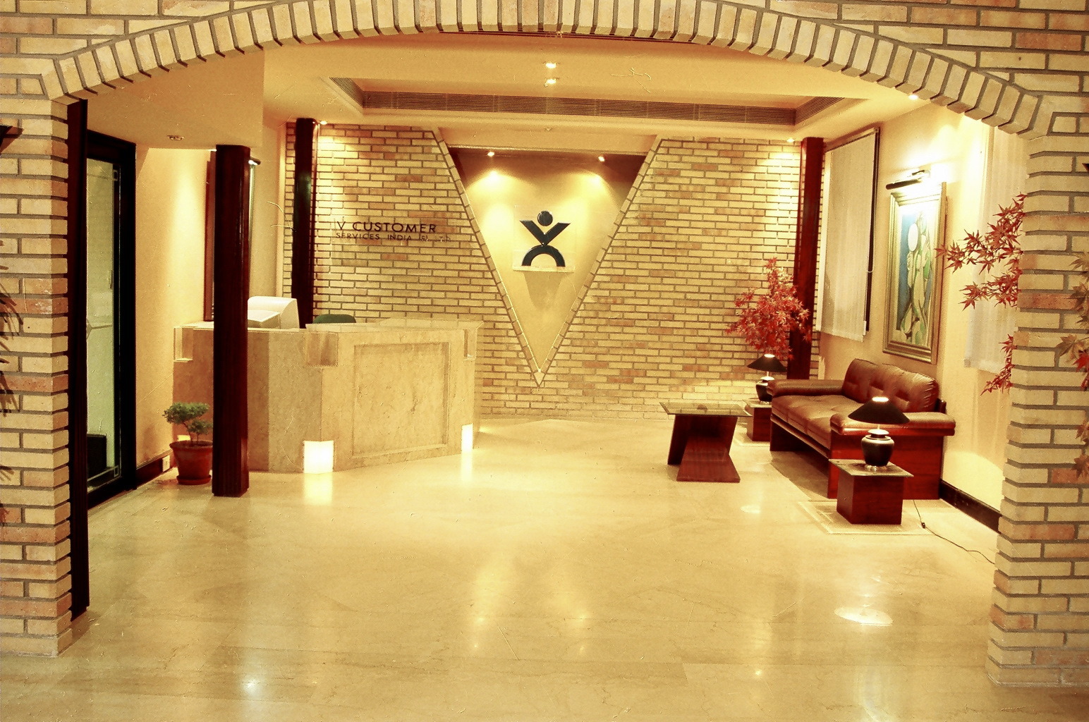 Warmly lit vCustomer Delhi reception with a V-shaped recess, marble flooring and a seating area
