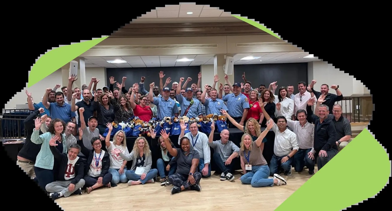 Group photograph published on Vector Solutions’ About Us page, showing participants waving beside uniformed first responders