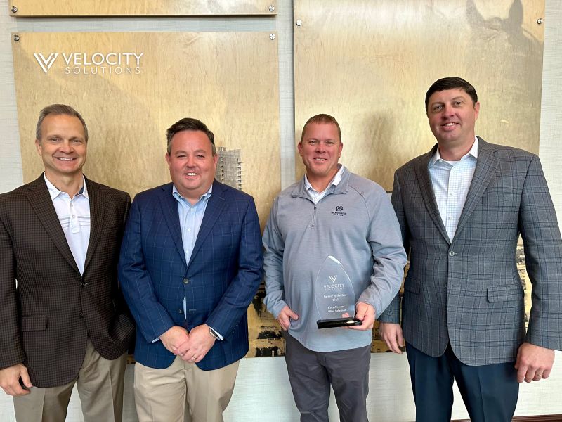 Four attendees at Velocity’s Executive Summit, with Cory Howard holding a partner award