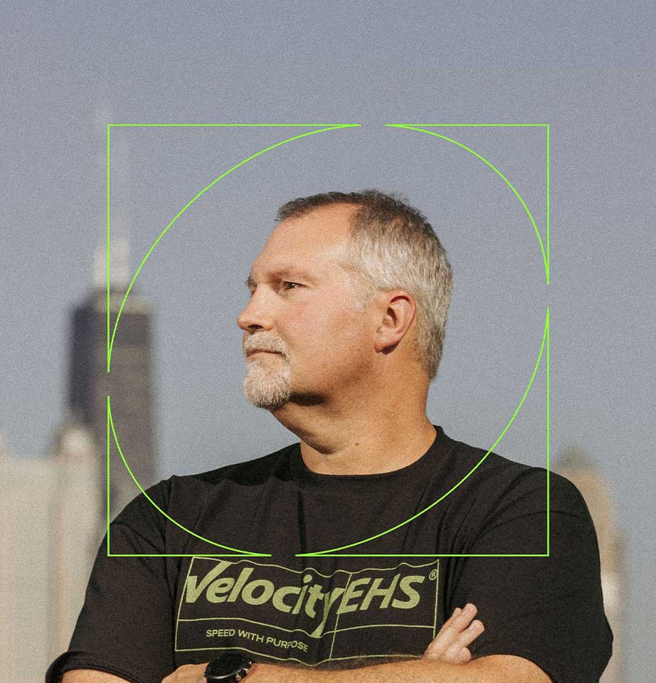 A VelocityEHS team member in a branded shirt, photographed against an industrial Chicago backdrop