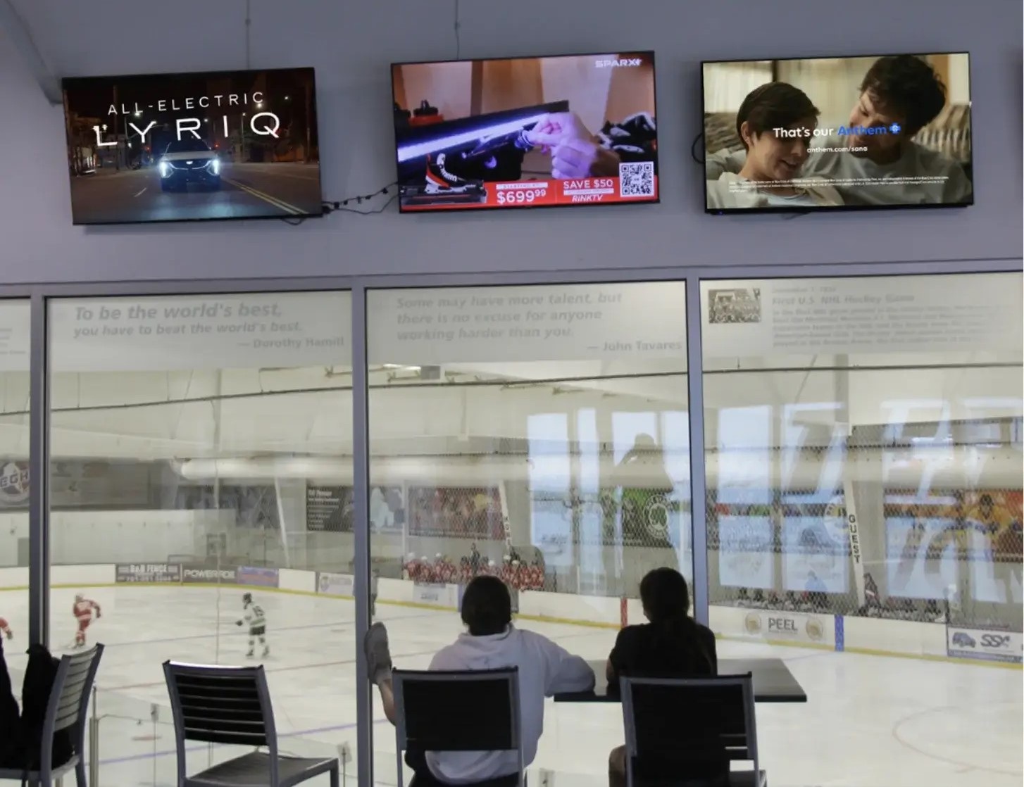 Advertising screens above spectator seating at an indoor ice hockey rink