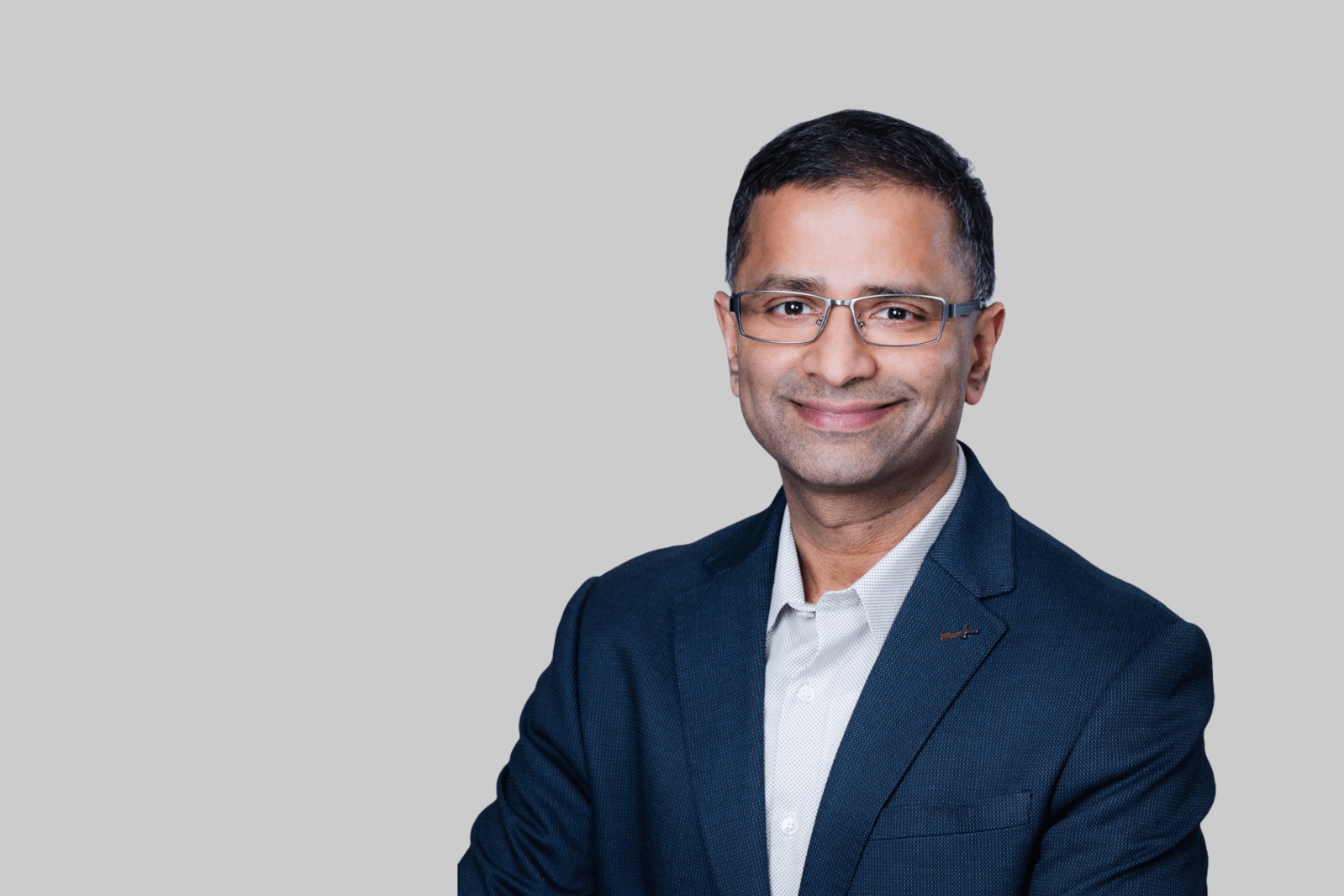 Venkat Rangapuram in a navy jacket, photographed against a light gray background