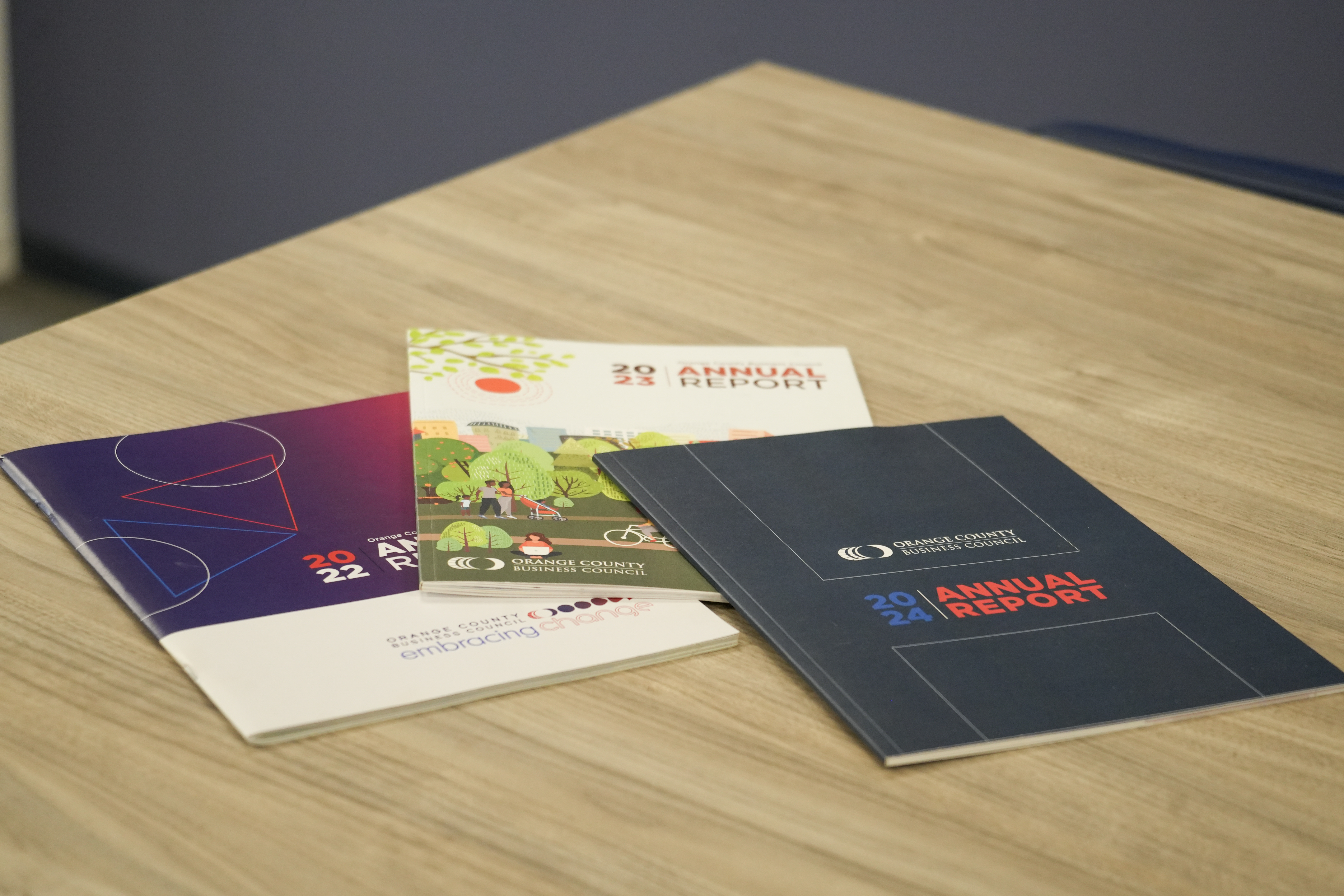Three Orange County Business Council annual reports displayed on a wooden table