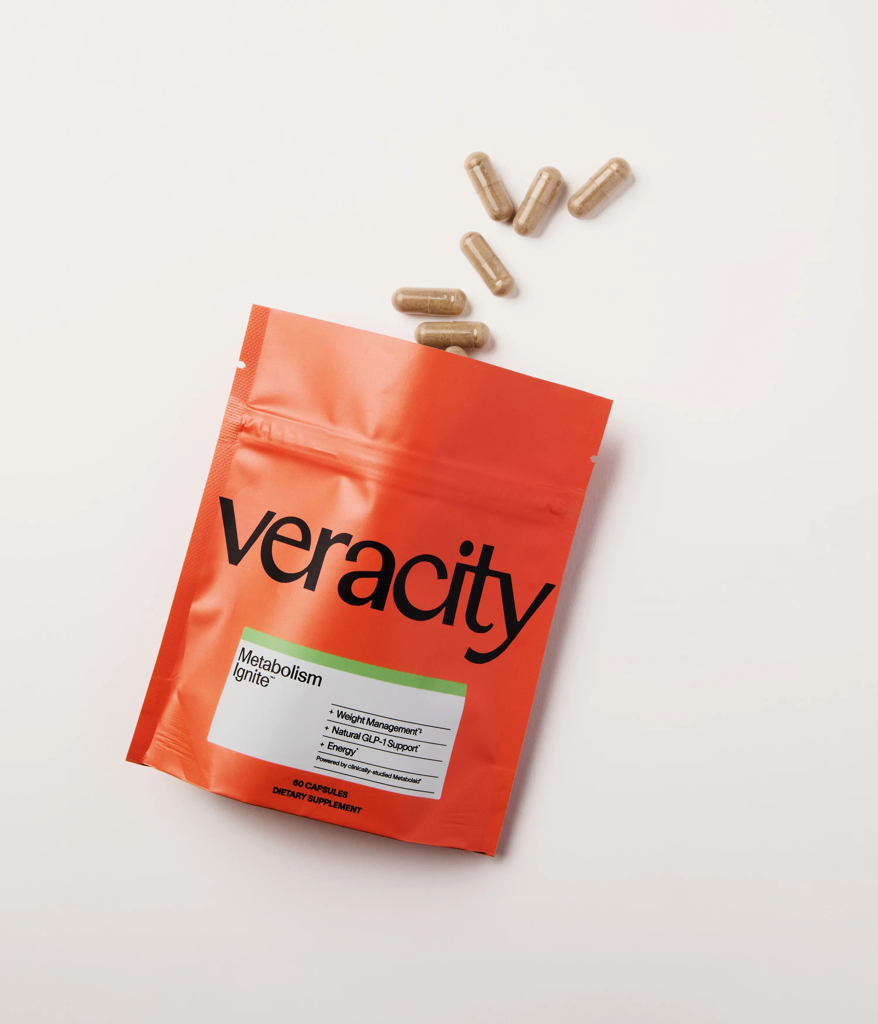 Orange Veracity Metabolism Ignite pouch with capsules on a pale surface