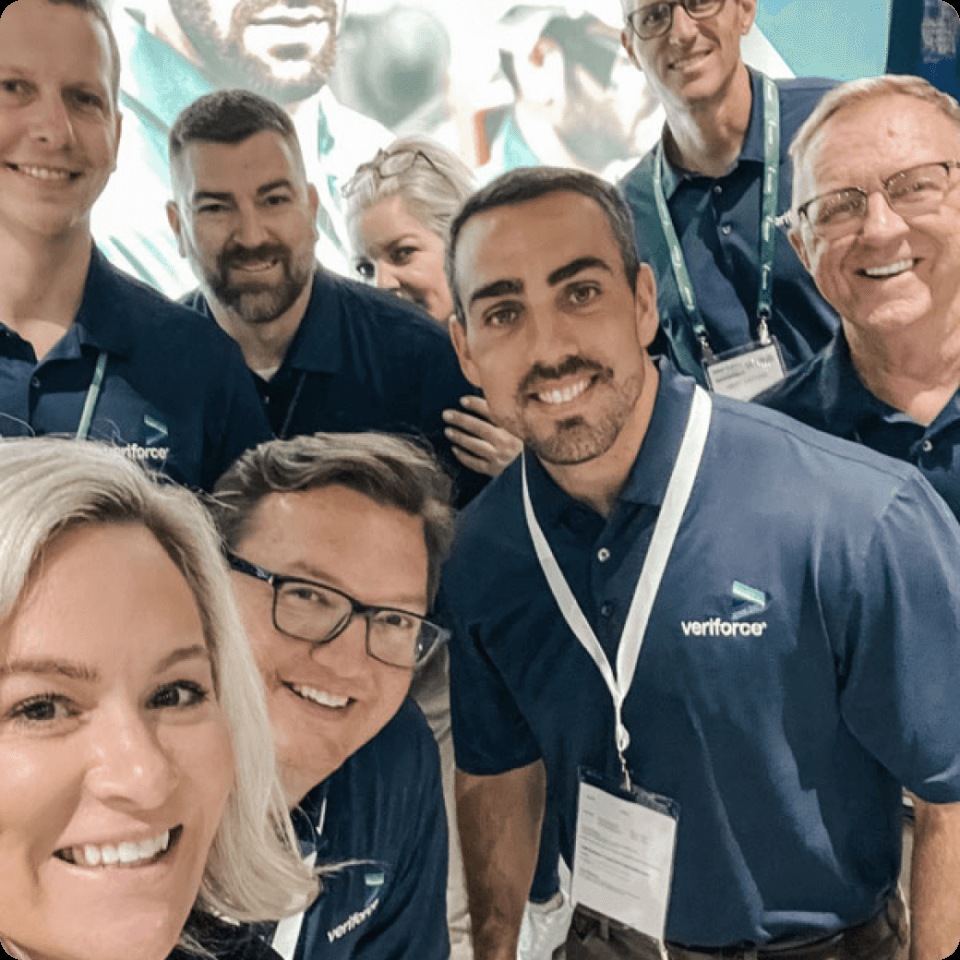 Veriforce colleagues in branded shirts posing for a group selfie