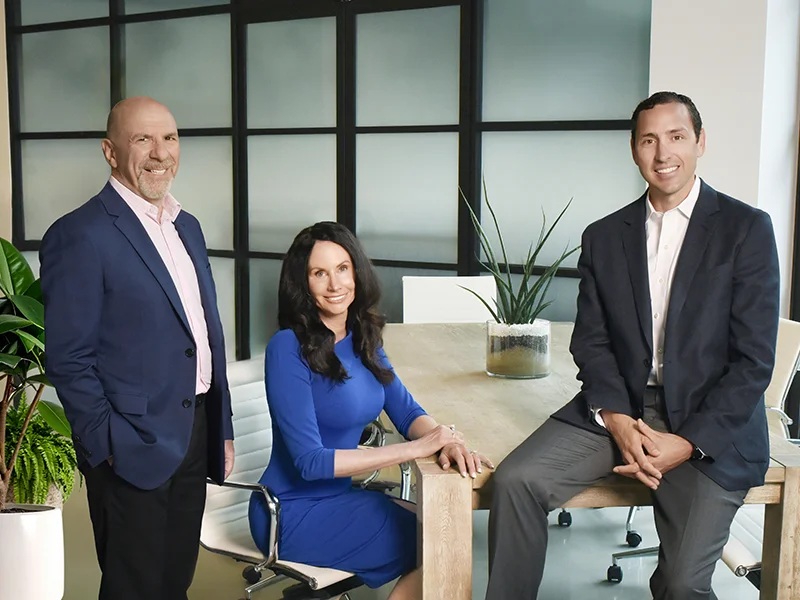 Three members of Verify’s leadership team gathered around a table in an office