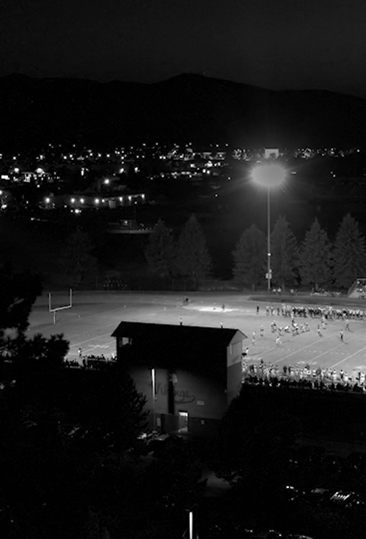 Black-and-white photograph of a football field under floodlights, from Vertical Raise’s website