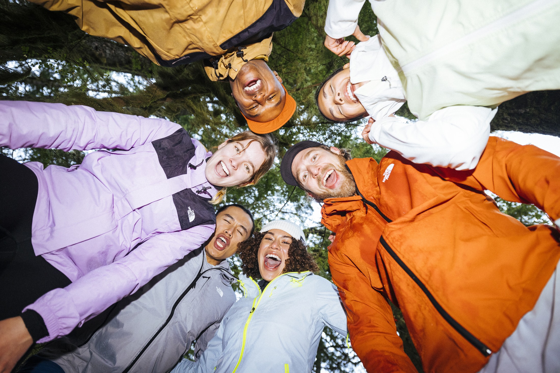 A circle of people wearing colorful The North Face jackets outdoors