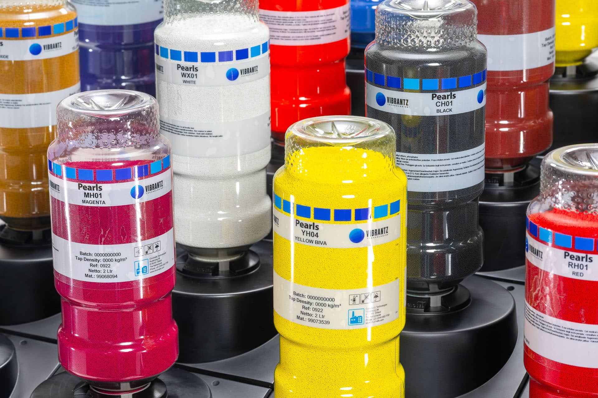 Transparent Pearls containers holding magenta, white, yellow, black and red solid colorants