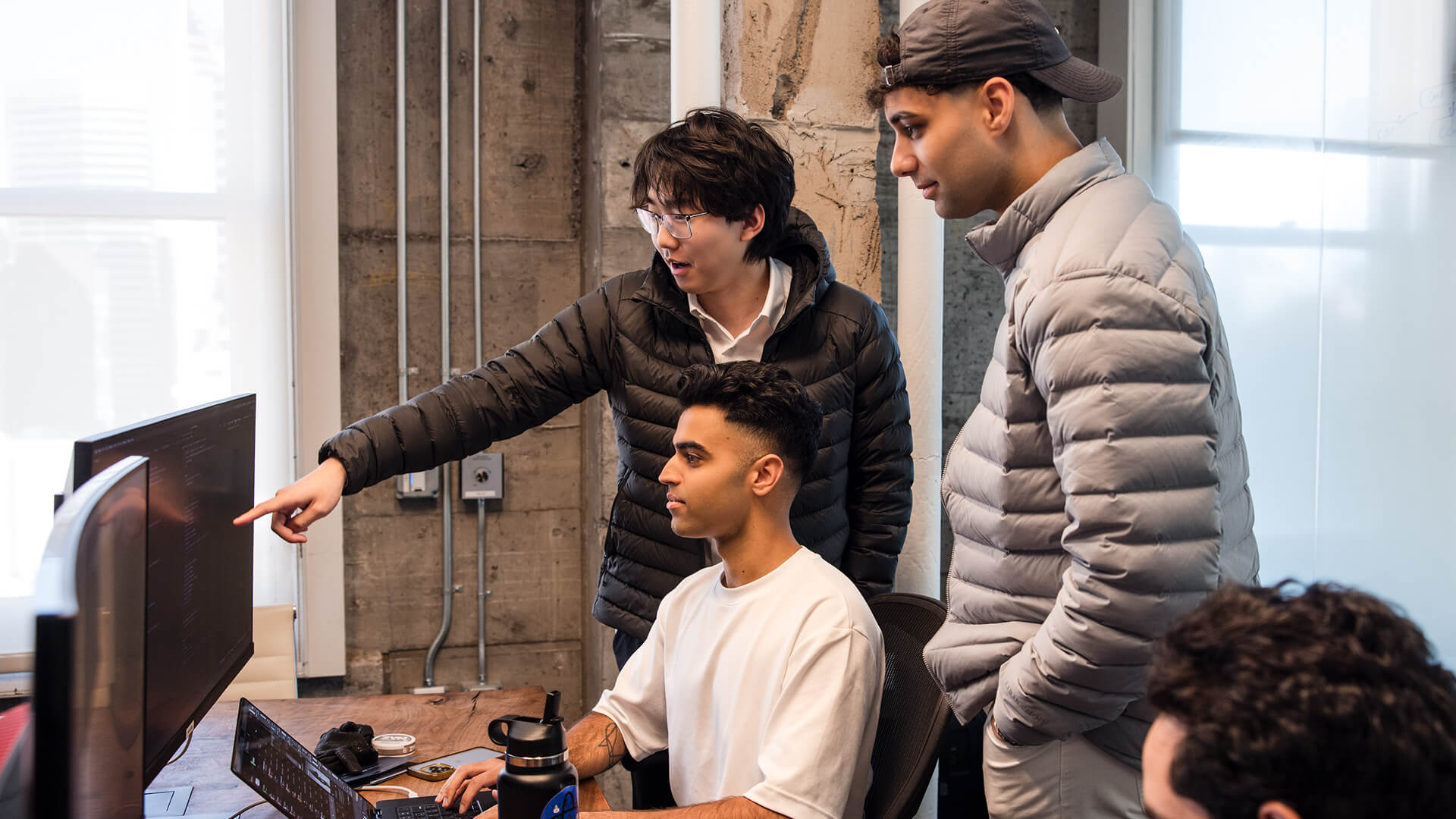 Slash team members discussing work around computer monitors in the office