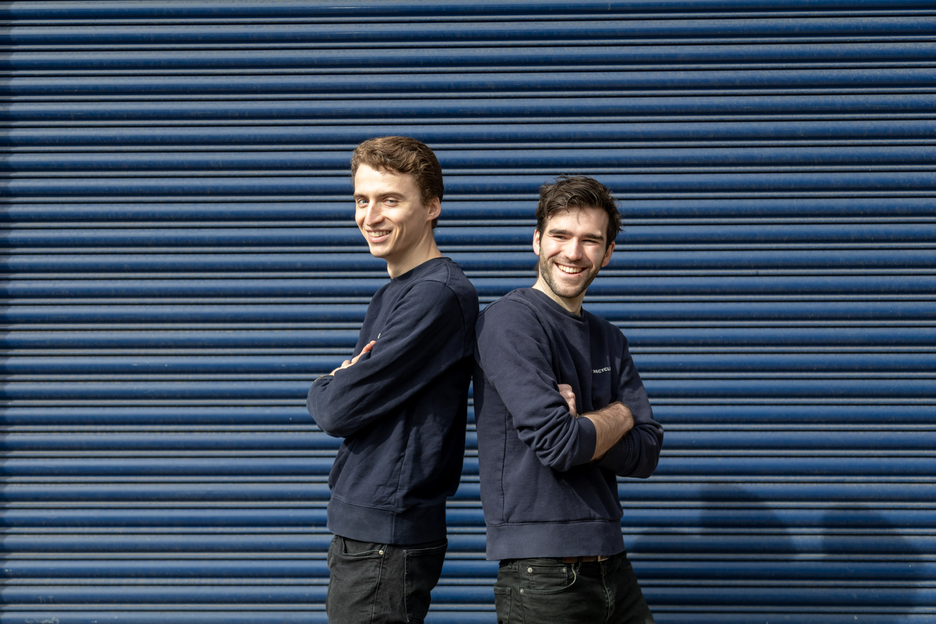 Victor Dewulf, left, and Peter Hedley standing back to back outside a blue industrial roller door