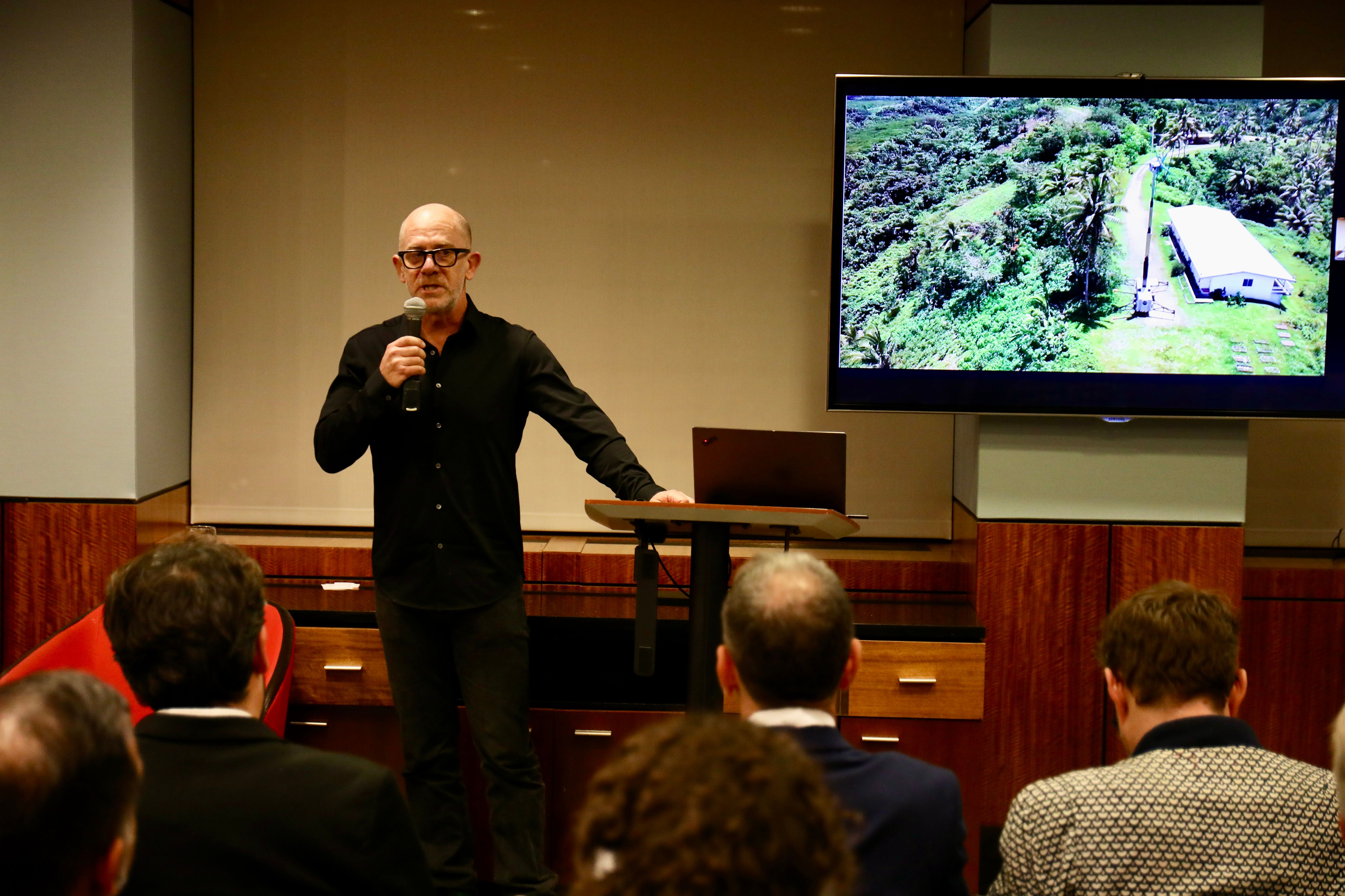Uprise Energy presenter speaks beside a screen showing a portable wind turbine