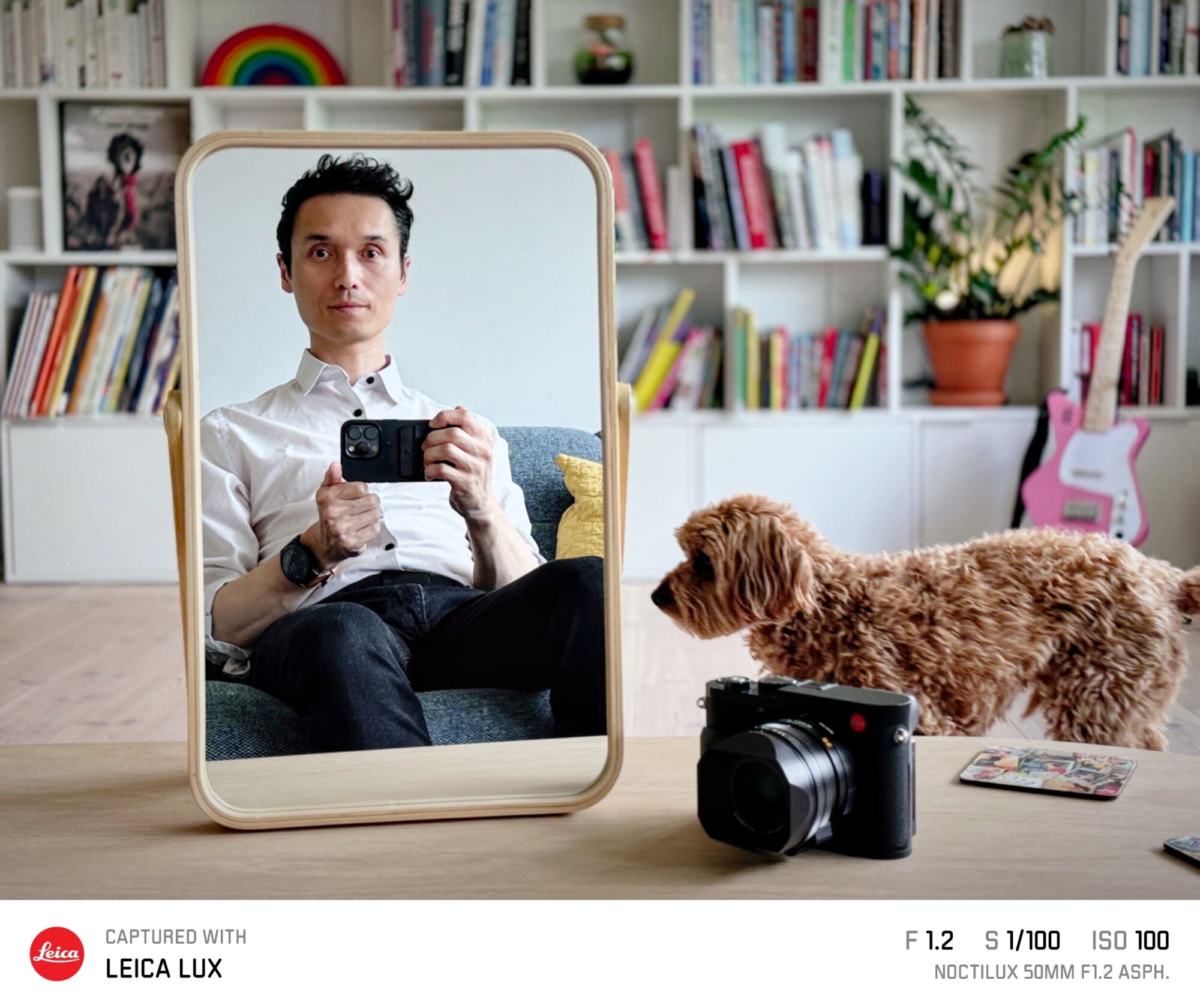 Victor Henning photographs his reflection at home, with books, a guitar, a dog and a Leica camera nearby