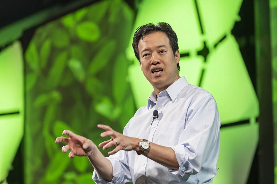 Victor W. Hwang speaking onstage against a green event backdrop
