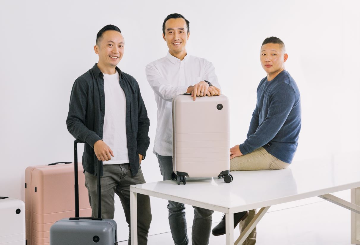 Monos cofounders standing and sitting beside their luggage