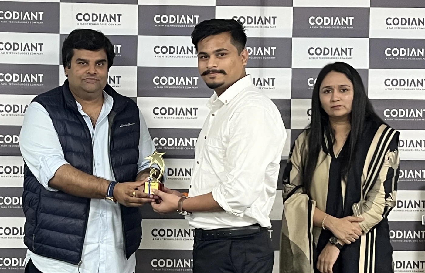 Vikrant Jain, left, presenting an award to a Codiant team member, with another colleague standing beside them.