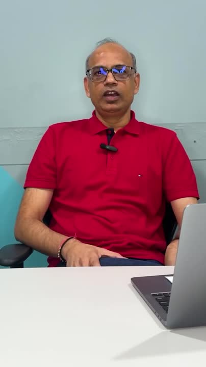 Vimal Saboo at a desk in a red polo shirt during Fibe’s Scam Defender video