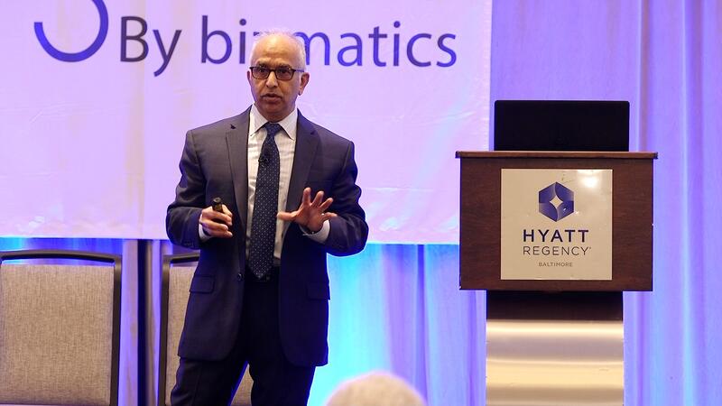 Vinay Deshpande speaks beside a lectern at a Bizmatics event at the Hyatt Regency Baltimore
