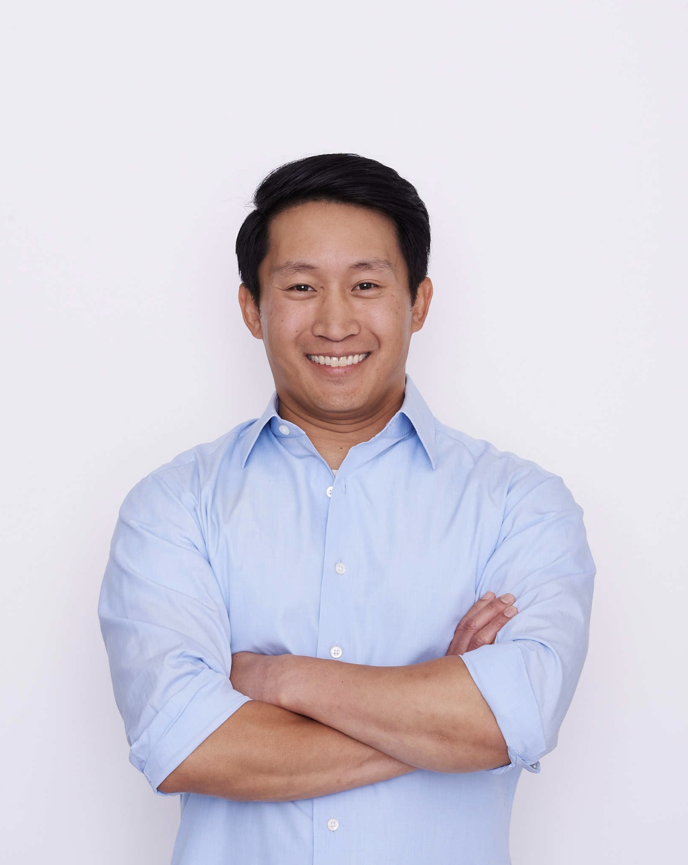 Vincent Liu in a blue shirt, smiling with his arms folded