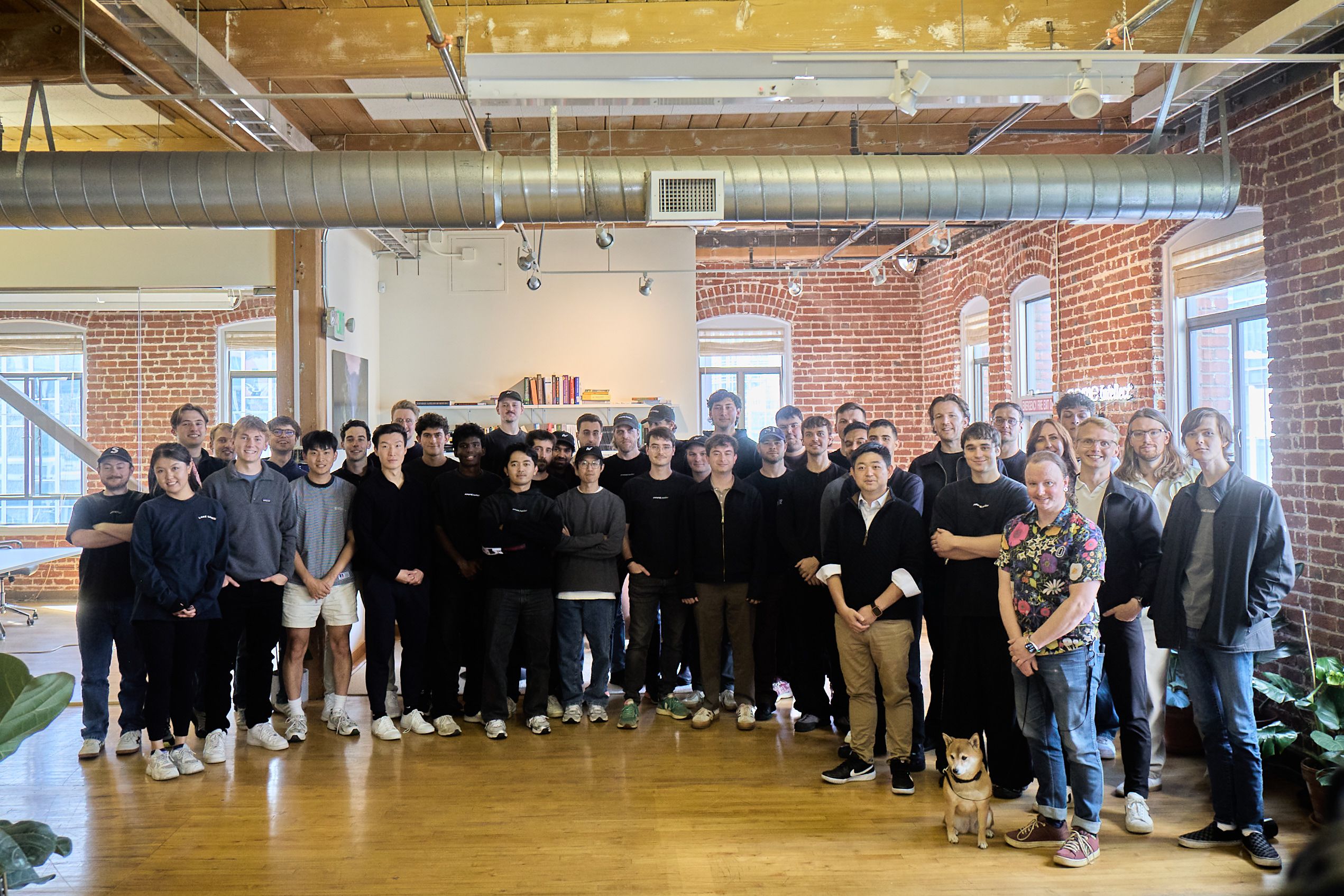 The Prime Intellect team gathered in an office with exposed brick and timber