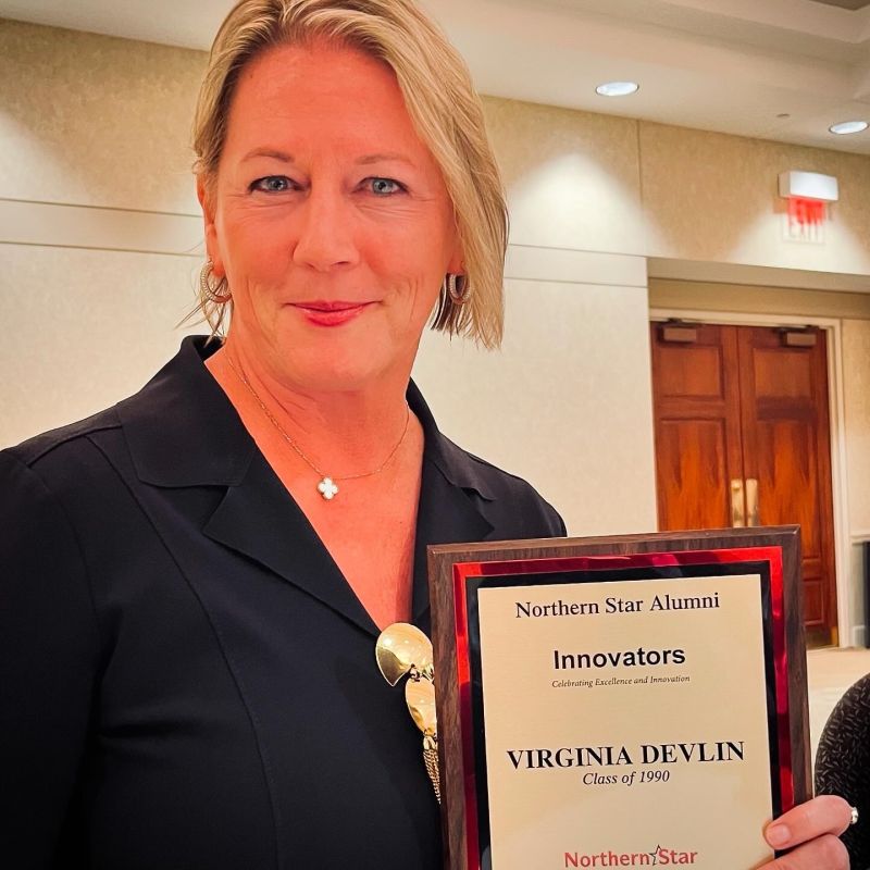 Virginia Devlin holding her Northern Star Alumni Innovators award, marked Class of 1990.
