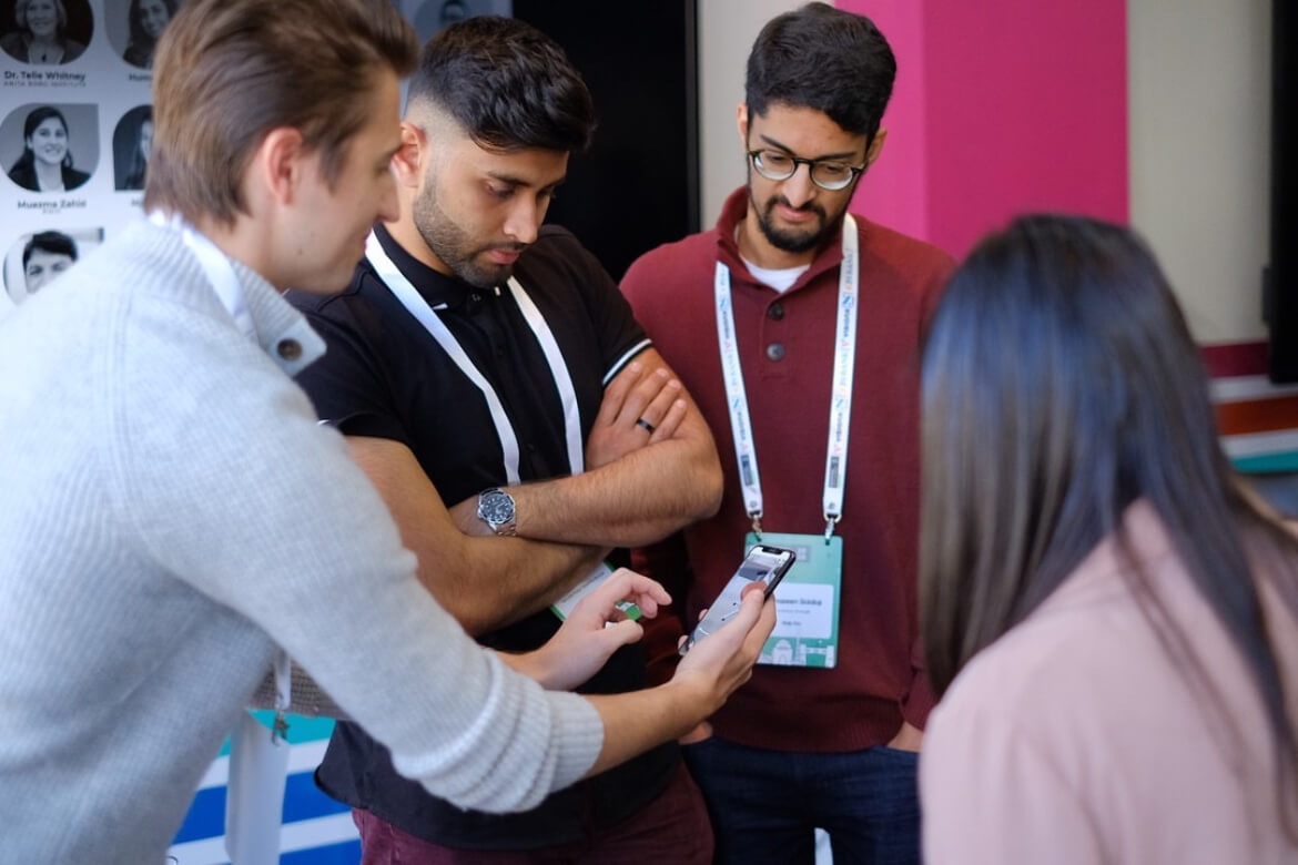 People gather around a smartphone in a photograph published on VisionX’s about page