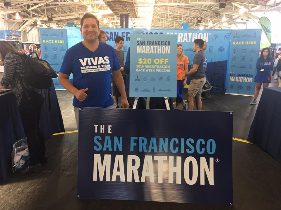 Luis Vivas standing beside printed San Francisco Marathon graphics