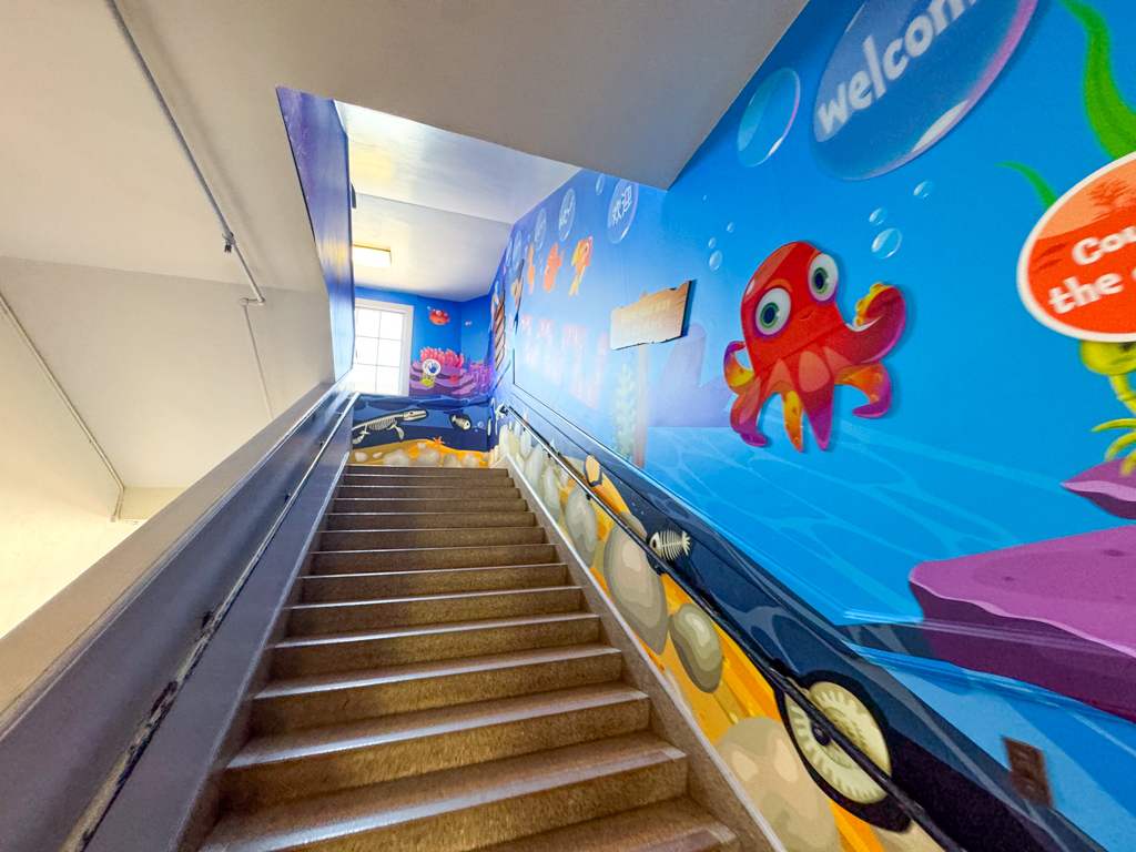 Blue underwater wall graphics installed along a school stairwell