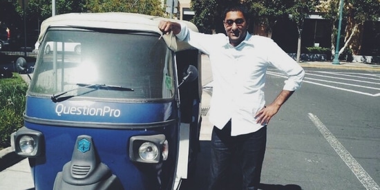 Vivek Bhaskaran leaning against the roof of a QuestionPro auto-rickshaw